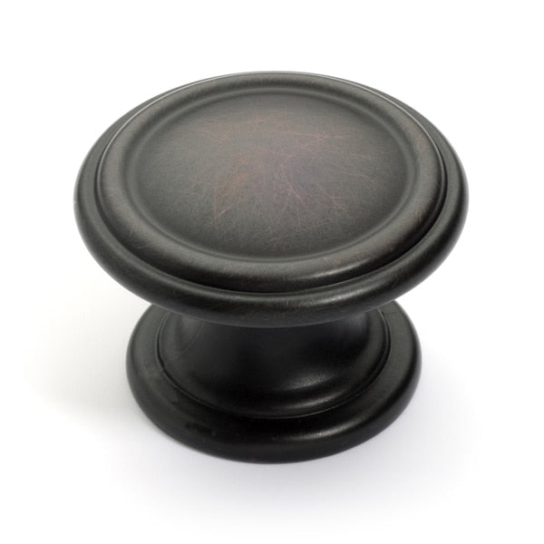 One and three eighths inch diameter drawer knob in oil rubbed bronze finish with slightly raised edges and the same size of base as the diameter of the grip