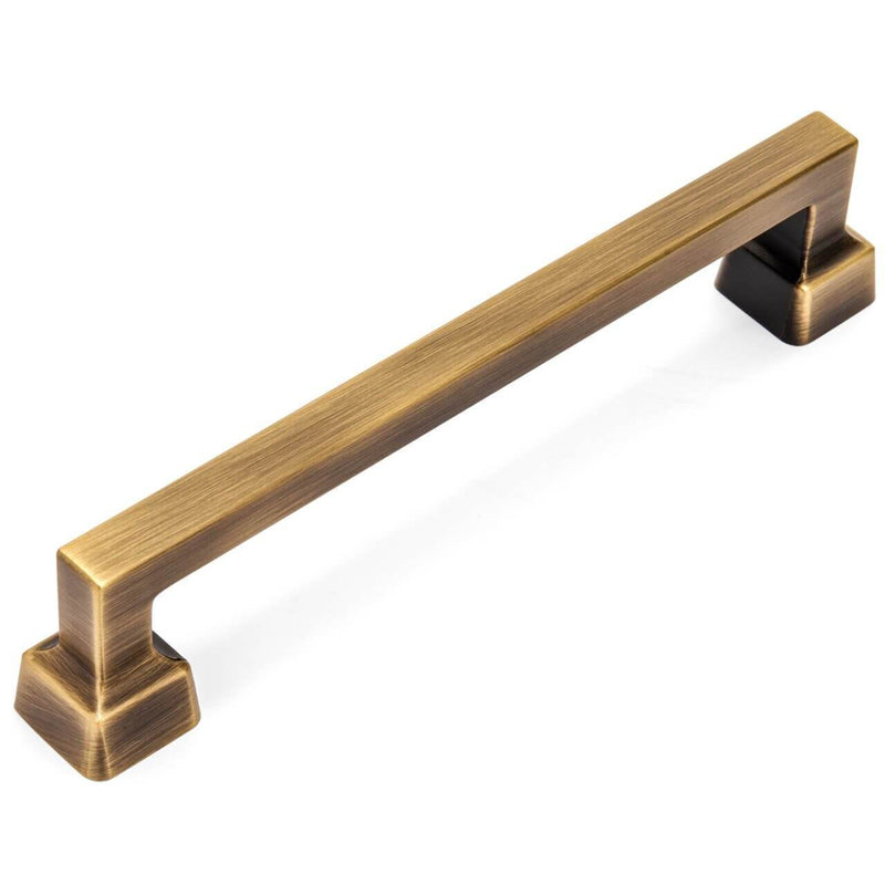 Square cabinet pull with square edges and wide feet set on a white background. The Cosmas 1481-128BAB pull is a modern design in brushed antique brass for kitchen cabinets. 