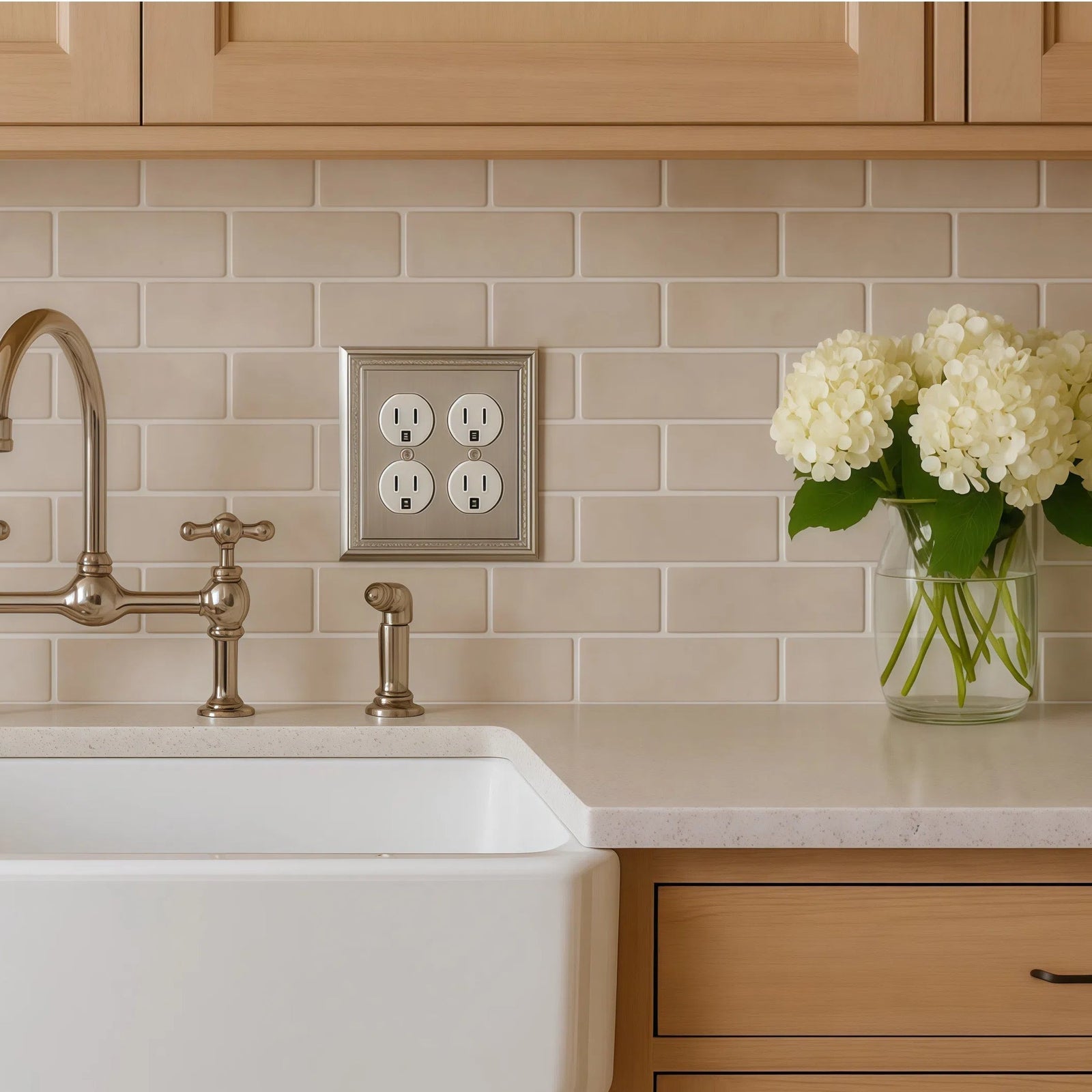 satin nickel wall outlet cover on a tan subway tile back splash in farmhouse modern kitchen