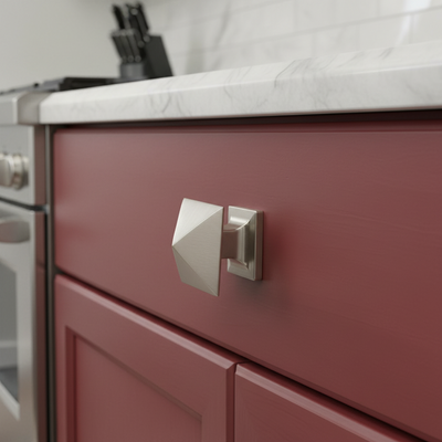Close-up of a red kitchen cabinet with a silver geometric handle.