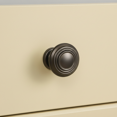 Graphite gray cabinet knob installed on a yellow cabinet drawer 
