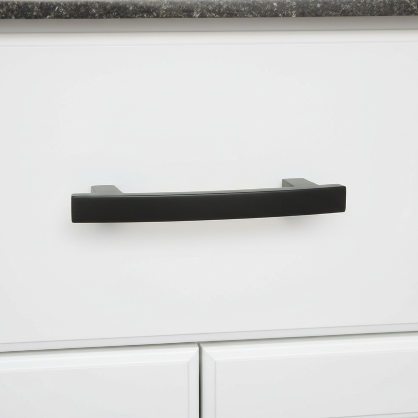Black cabinet handle on a white cabinet with a dark countertop.