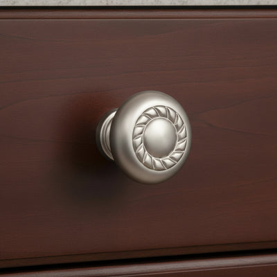 Silver cabinet knob with decorative pattern on a white background