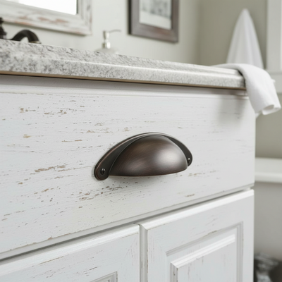 bronze brown cabinet handle on a weathered white cabinet with a towel in the background