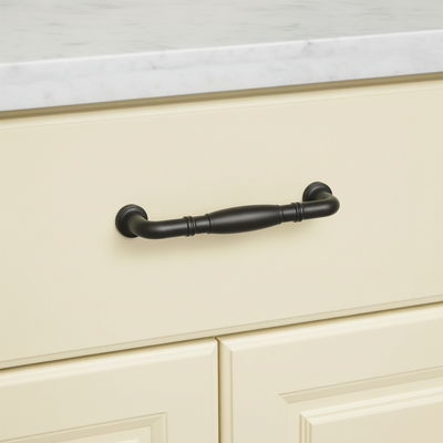 oil rubbed bronze cabinet handle on a beige cabinet with a white countertop.