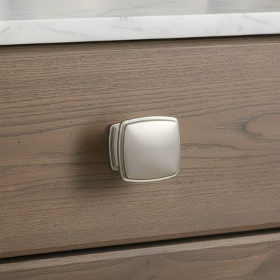 Brushed nickel cabinet knob on a wood drawer
