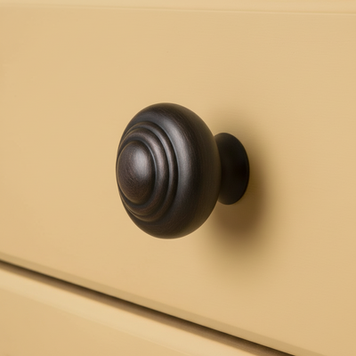 Oil rubbed bronze drawer knob with raised rings design on a yellow drawer 
