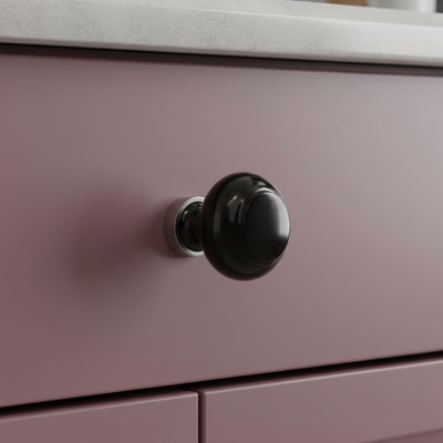 Black glass drawer knob with satin nickel base on a deep pink cabinet drawer