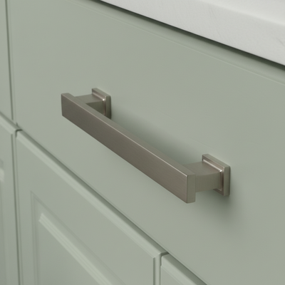 Cabinet handle on a light green cabinet with a white countertop.