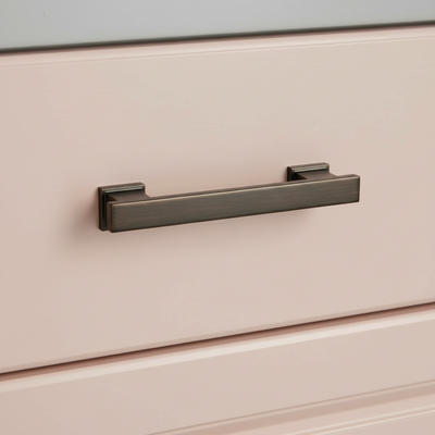 Close-up of a bronze rubbed handle on a light-colored drawer