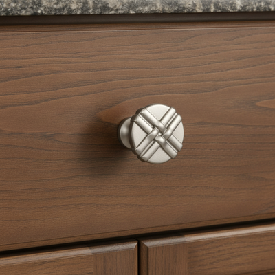 brushed satin nickel decoratie knob on a brown wood cabinet drawer