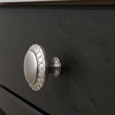 Decorative satin nickel cabinet knob  on a black cabinet drawer