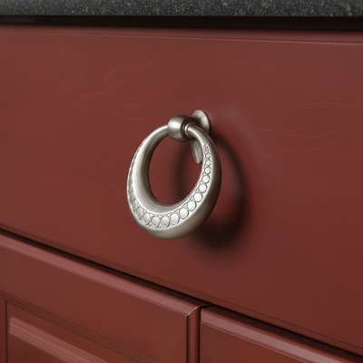 Close-up of a red cabinet with a satin nickel ring handle