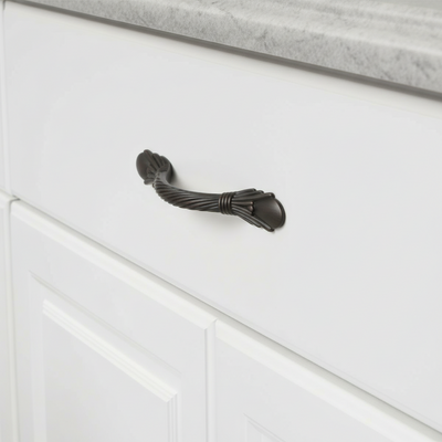 Oil rubbed bronze decorative cabinet pull on a white drawer 
