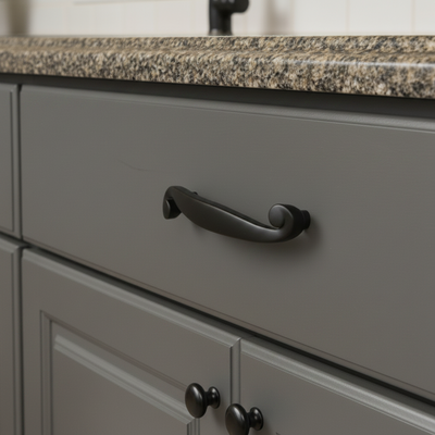 Close-up of black handles and a granite countertop.