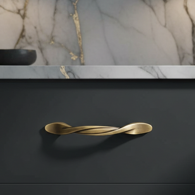 Gold twisted handle on a black surface with marble background