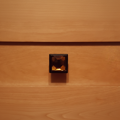 amber glass cabinet knob with oil rubbed bronze finish on a wood drawer 

