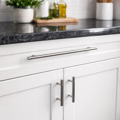 White kitchen cabinets with silver handles on a dark countertop.