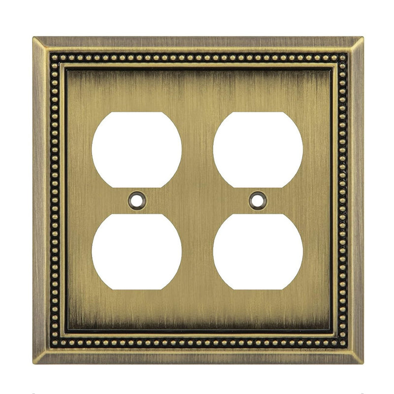 Decorative brass wall outlet cover with four sockets on a white background