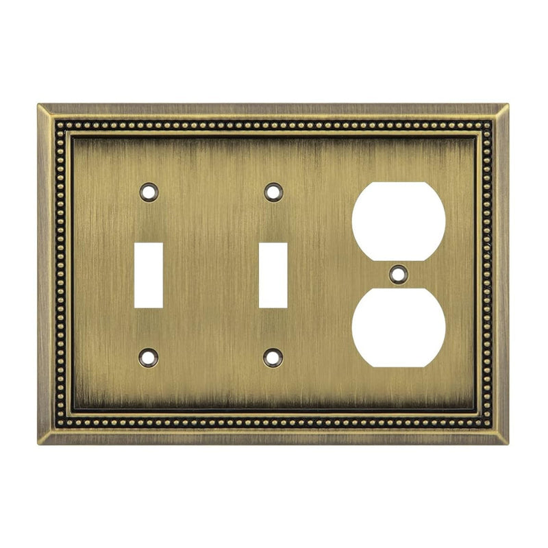 Decorative antique brass switch plate with two toggle switches and one outlet on a white background