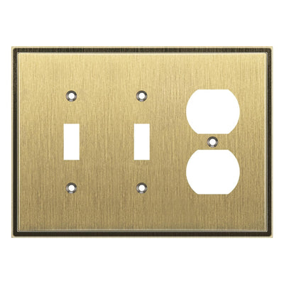 Brass switch plate with two toggle switches and one outlet on a white background