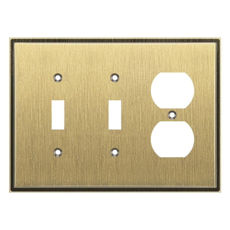 Brass switch plate with two toggle switches and one outlet on a white background