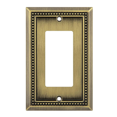 Antique brass wall plate with beaded border on a white background
