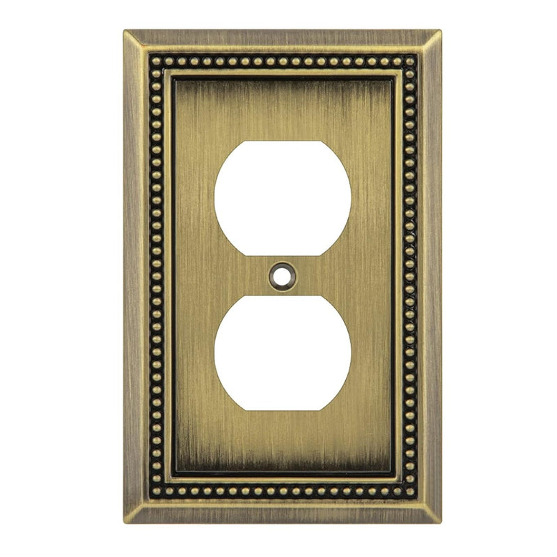 Antique brass wall outlet cover with beaded border on a white background