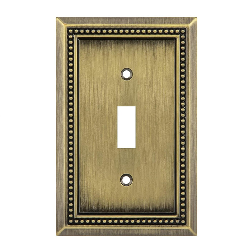 Antique brass single toggle switch plate with decorative border on a white background