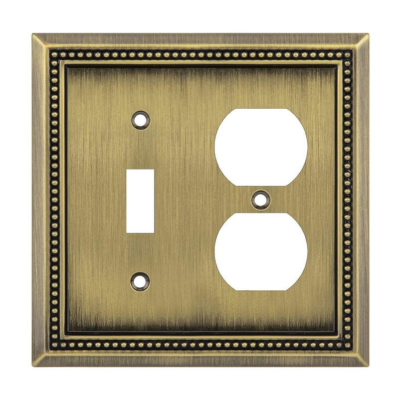 Decorative brass switch plate with a single toggle and duplex outlet design.