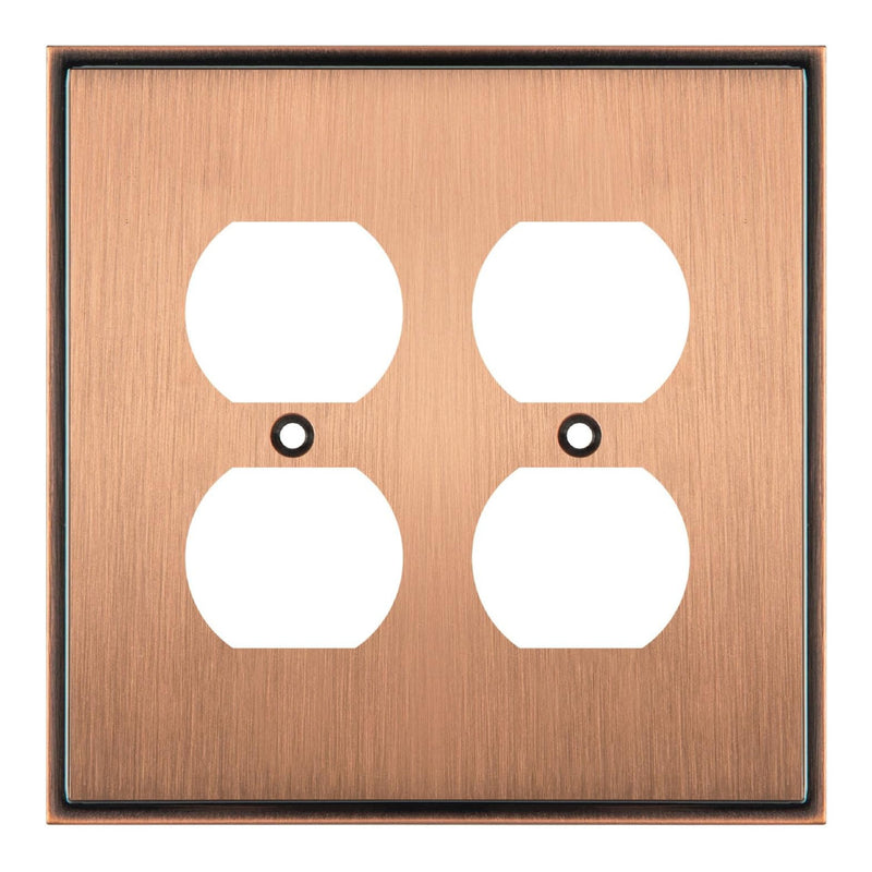 Copper double electrical outlet cover with white inserts on a white background