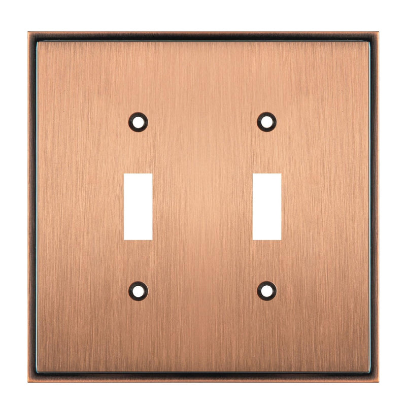 Copper double toggle switch plate with two white switches on a white background