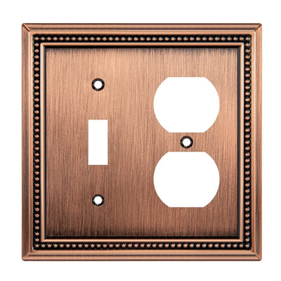 Decorative copper switch plate with a single toggle and duplex outlet design on a white background.