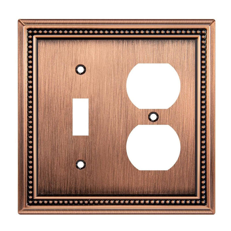Decorative copper switch plate with a single toggle and duplex outlet design on a white background.