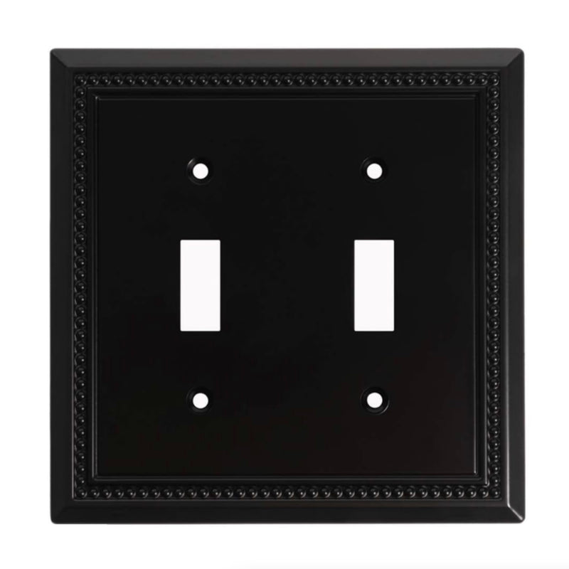 Black double toggle switch plate with decorative border on a white background
