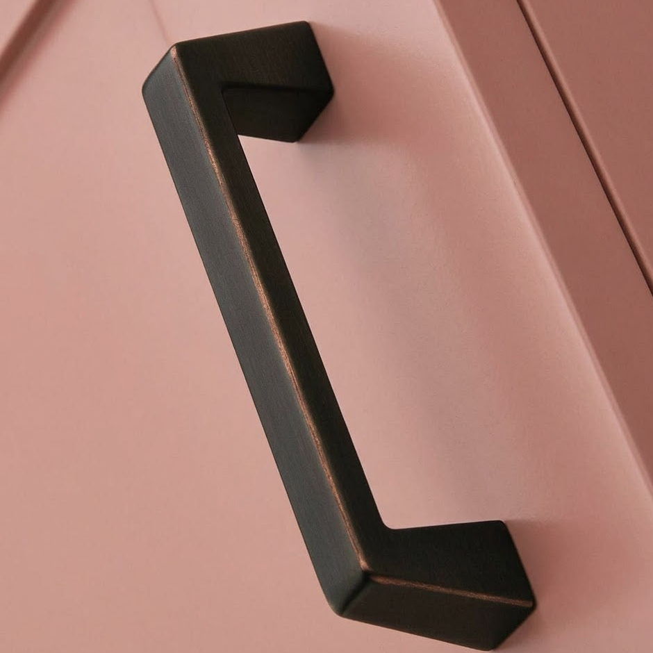Bronze cabinet handle on a pink cabinet