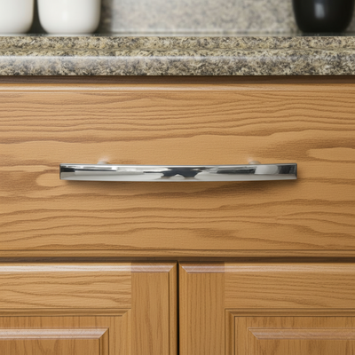 Close-up of a wooden cabinet with a shiny silver handle on a granite countertop.
