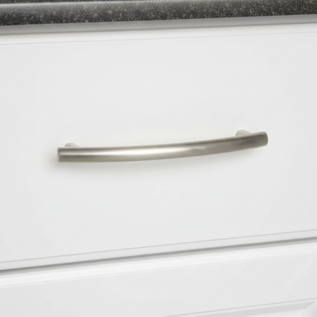 Close-up of a white cabinet drawer  with a satin nickel cabinet handle on a black countertop.