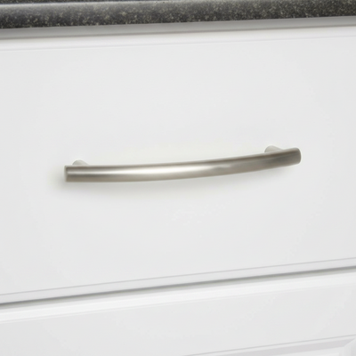 Close-up of a white cabinet drawer  with a satin nickel cabinet handle on a black countertop.