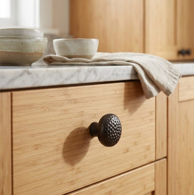 Wooden drawer with a textured knob in a kitchen setting