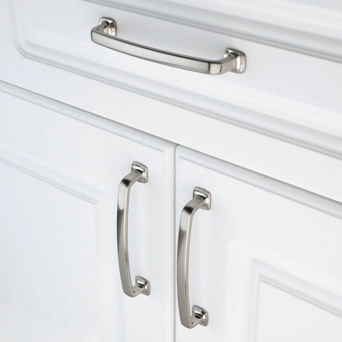 Satin nickel brushed nickel cabinet pulls on a white drawer and on white cabinet door. 