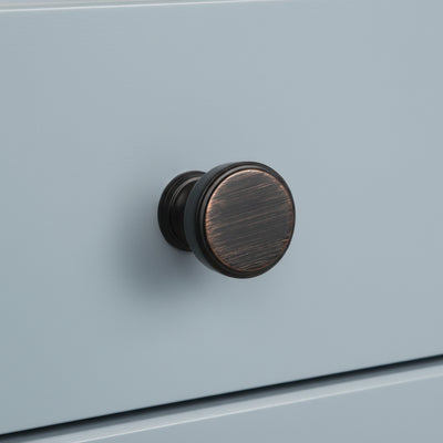 round cabinet knob oil rubbed bronze on a blue cabinet drawer 
