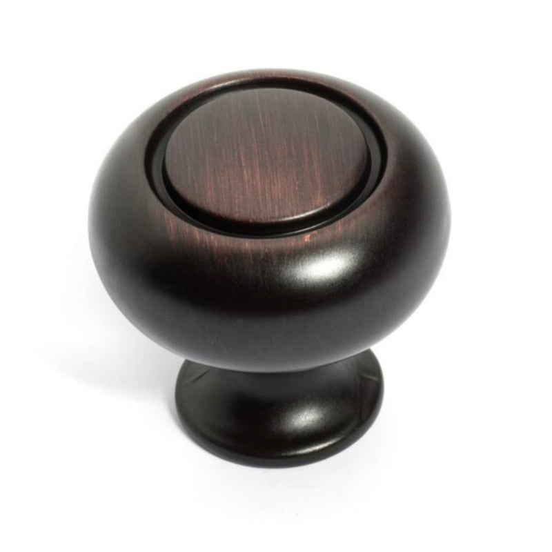 Round cabinet knob in oil rubbed bronze finish with a ring shaped cavity on the face and one and three sixteenths inch diameter