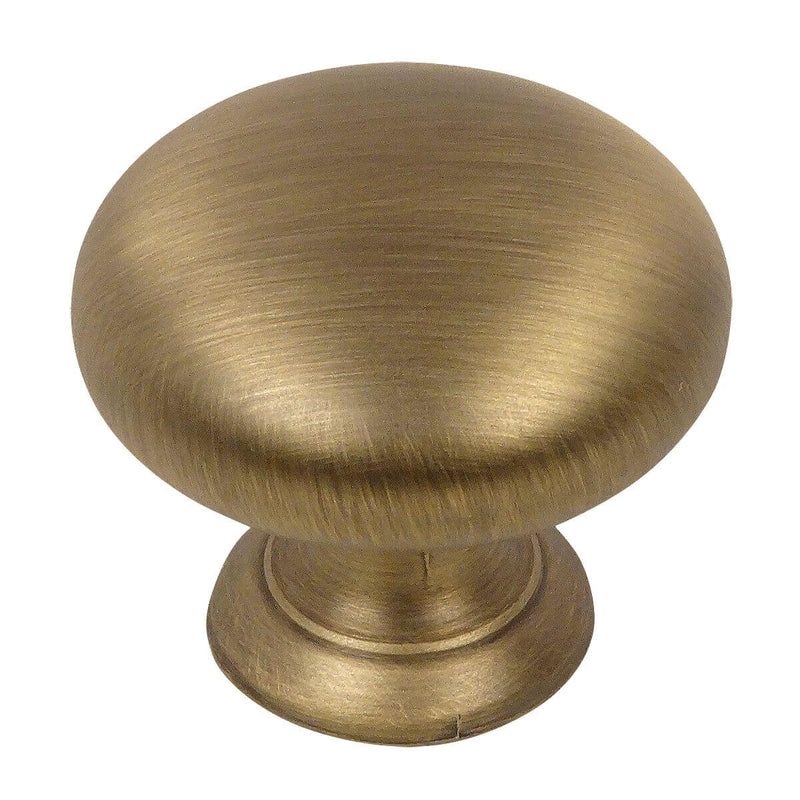 Round cabinet knob in brushed antique brass finish with one and a quarter inch diameter