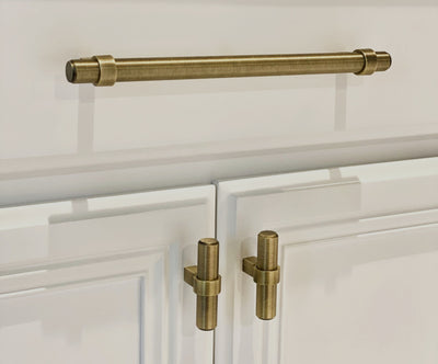 Brushed antique brass bar pull with two knobs mounted vertically below