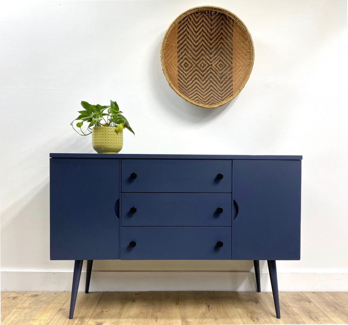 Navy blue restored art deco hutch with black cabinet knobs and yellow vase on top