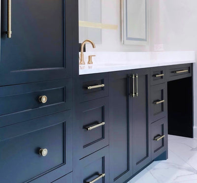 Bathroom with blue cabinets, white tile, and antique brass cabinet knobs and pulls