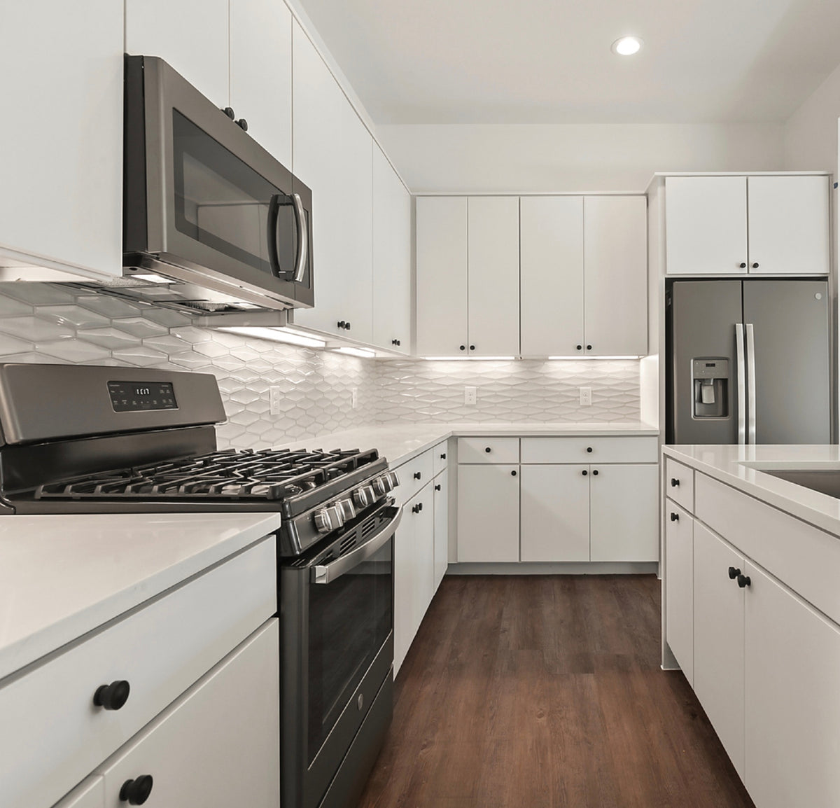 White plain kitchen cabinets with Cosmas black cabinet knobs and stainless steel appliances