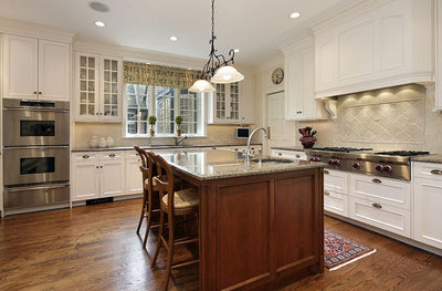 Kitchen with cup pulls and round knobs on white cabinets. The pulls are gunmetal graphite.