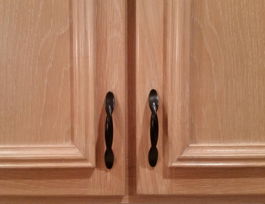 Black twist pulls by Cosmas 9009FB on wood cabinets.